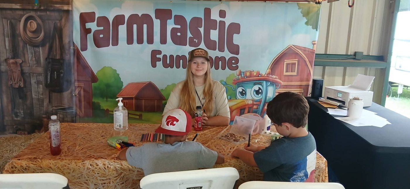 A staff member helping two boys make crafts at the Craft Creations Corner table