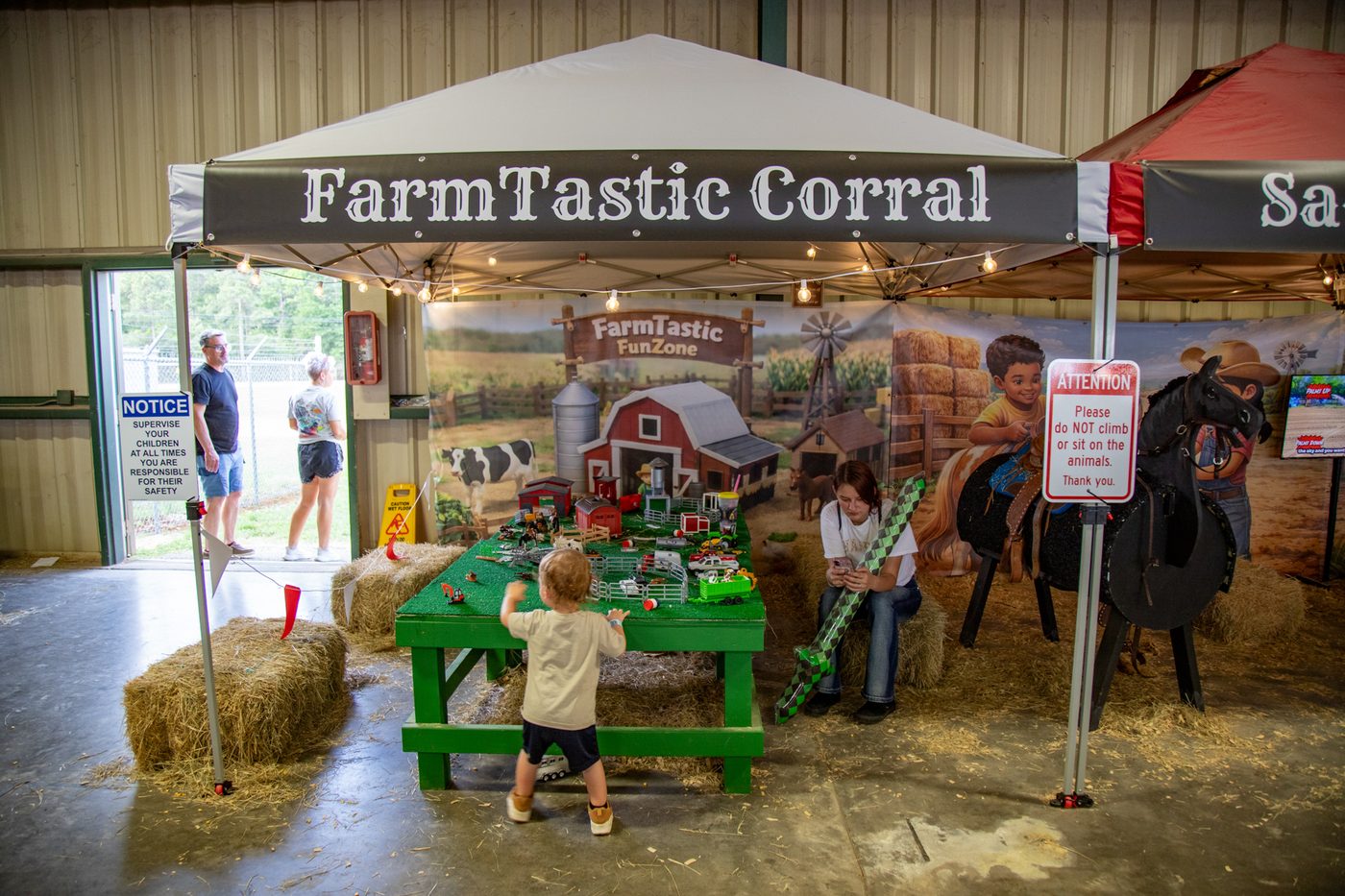 A child reaching for toy animals at the FarmTastic Corral play table