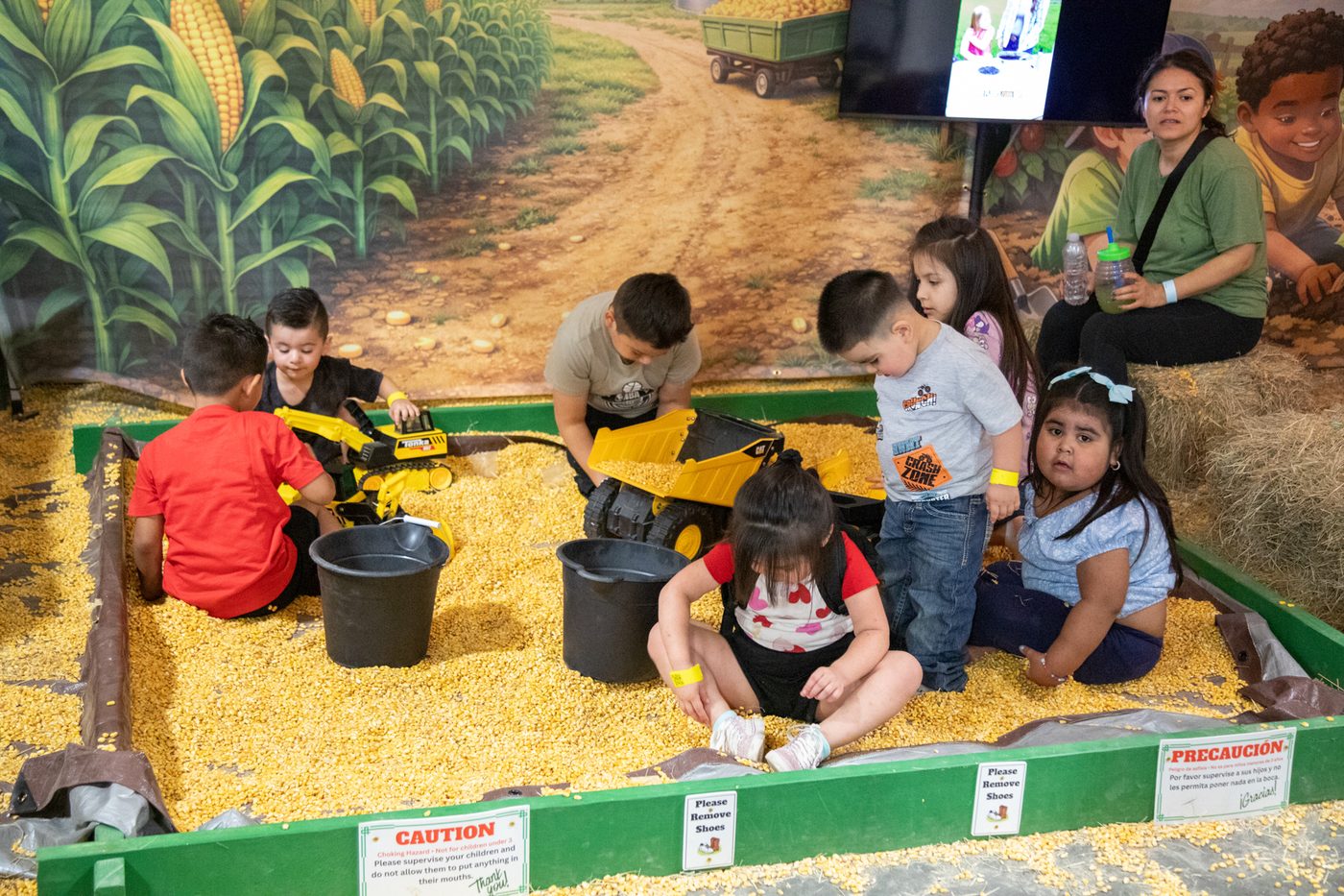 Kids digging with toy trucks in the corn-filled Kernel Corn-struction Zone